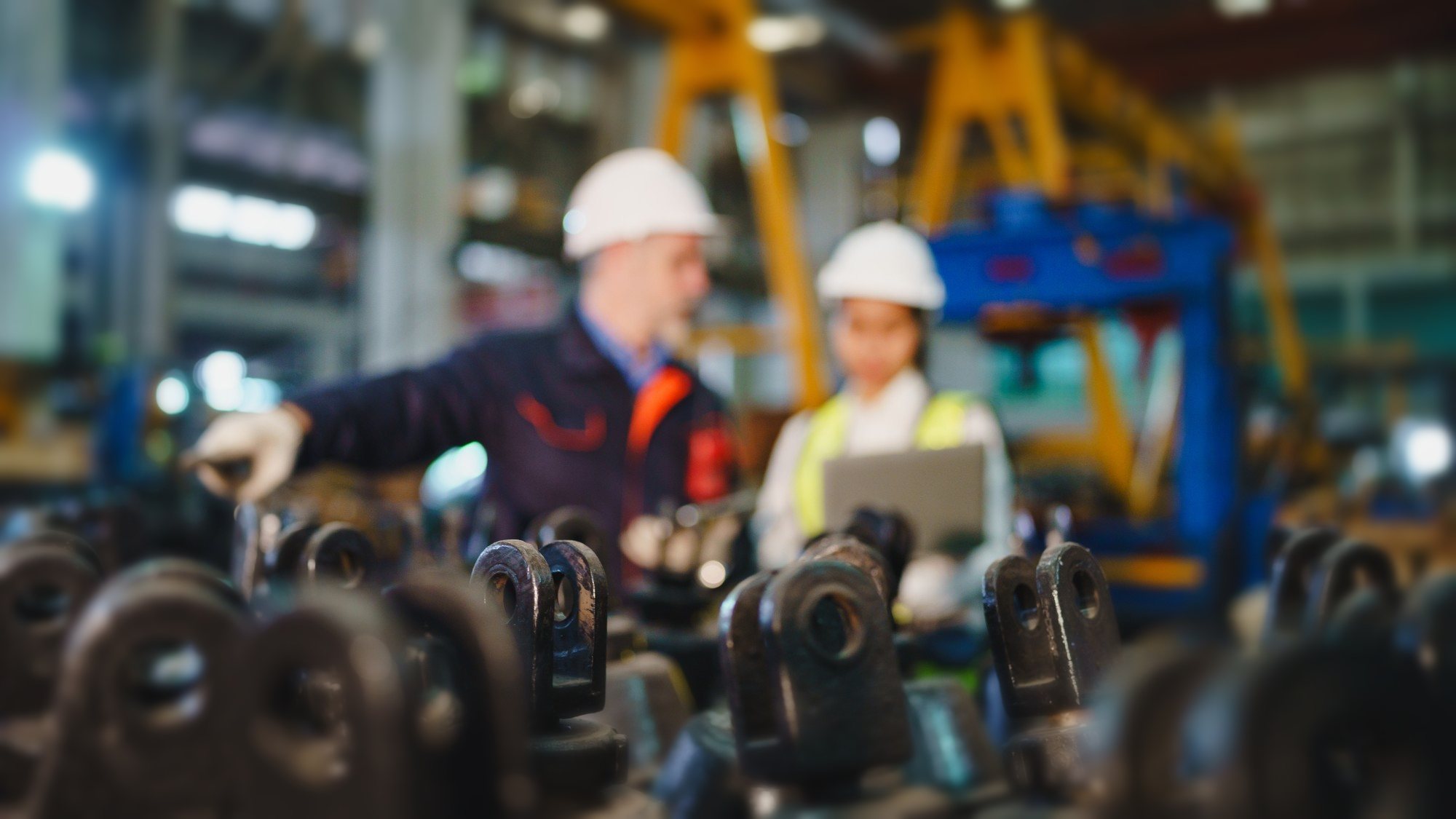 Two engineers in hard hats reviewing work on a factory floor