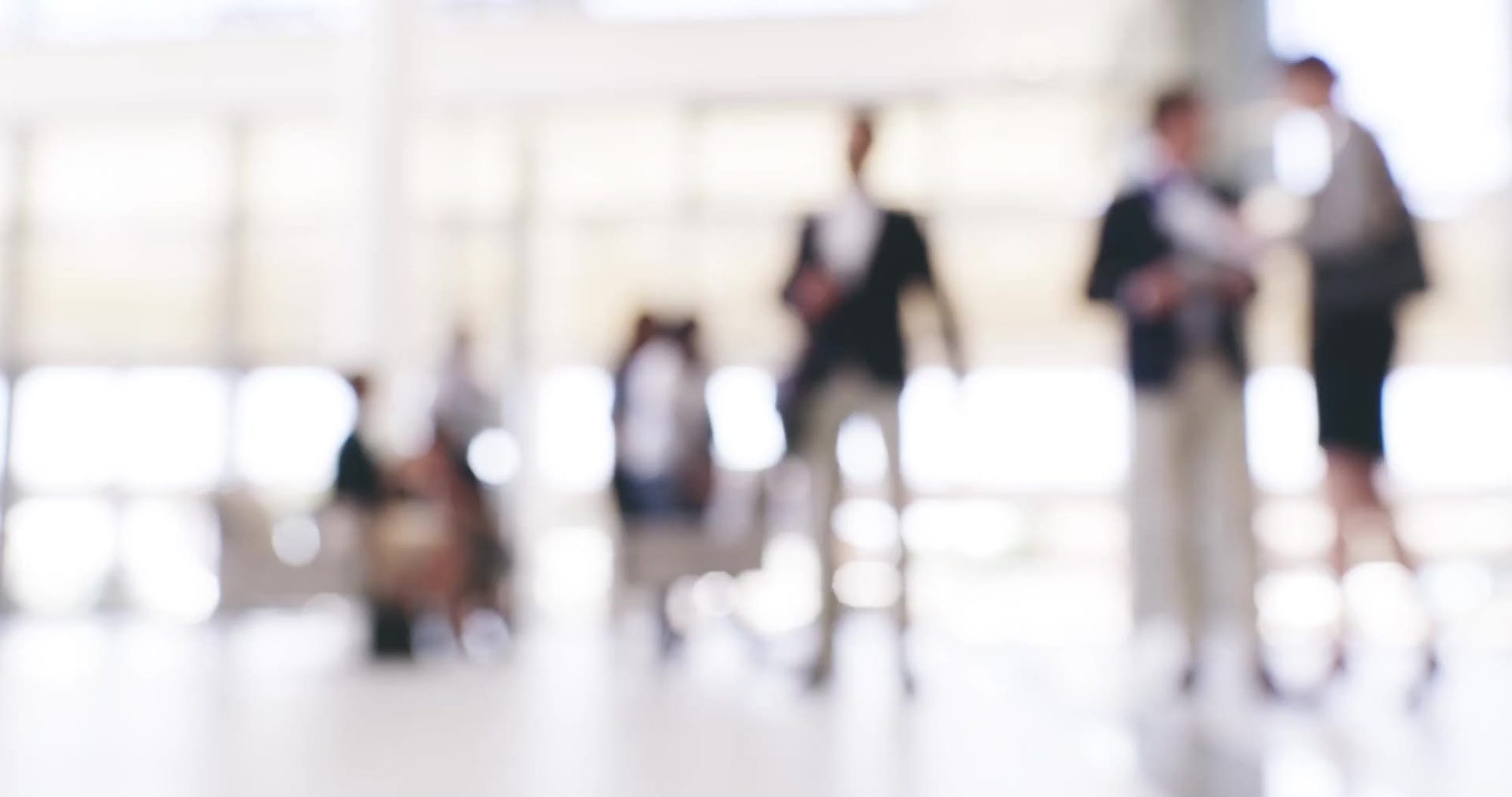 People in a bright office lobby, out of focus